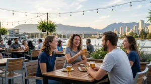 Friends laughing and enjoying drinks on a sunny Vancouver patio overlooking the water, wearing lightweight, comfortable cooling t-shirts for summer evenings.