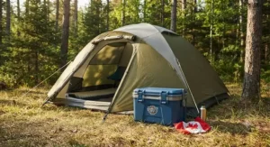 Durable small hard cooler for festivals placed next to a camping tent in Canada.