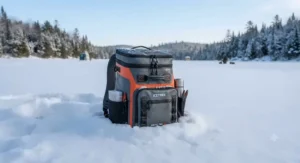 Durable and weatherproof backpack cooler for ice fishing sitting upright in deep winter snow.